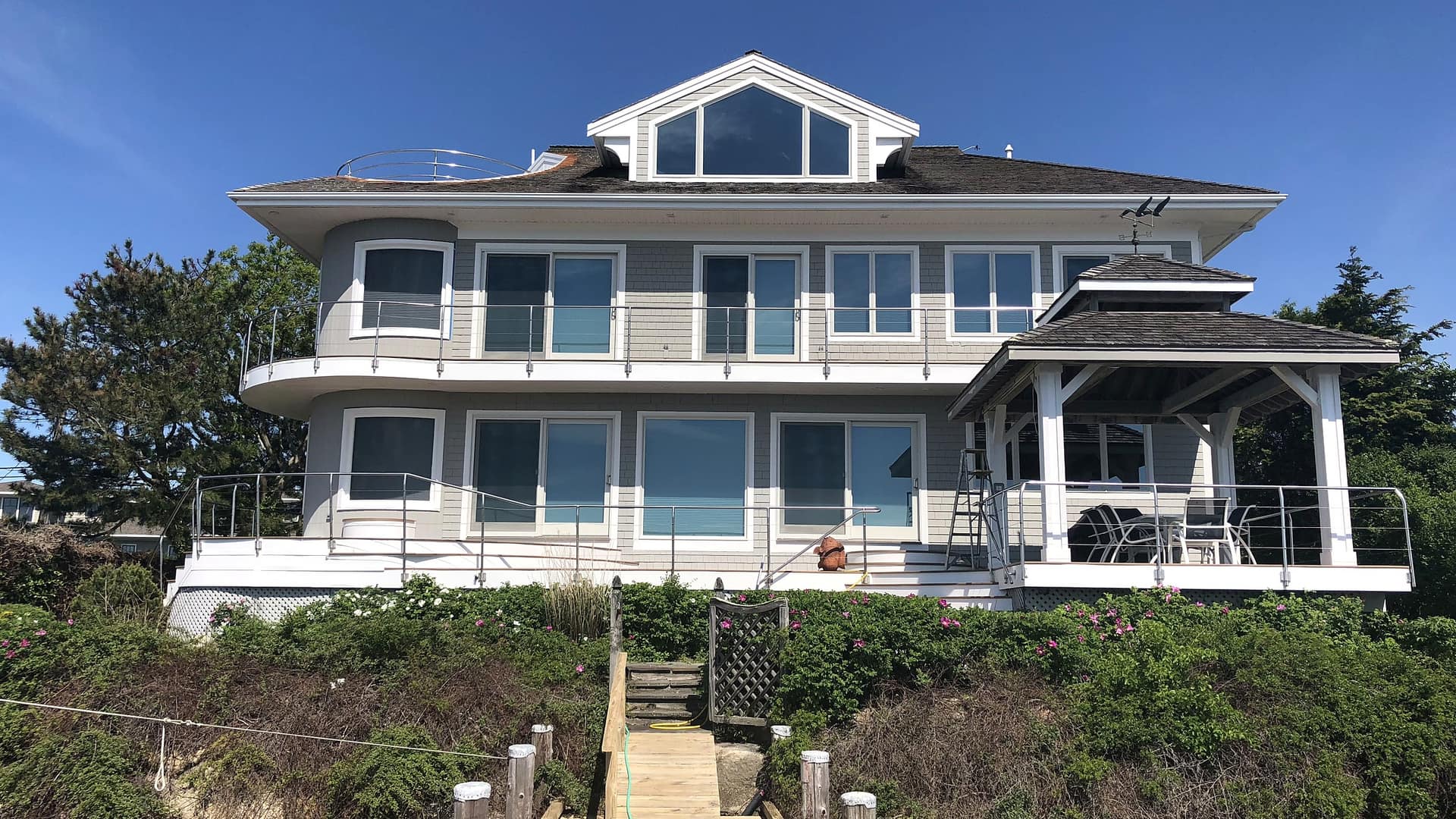 Waterfront Cape Cod exterior with gray shingles and white trim by Elite Painting Services